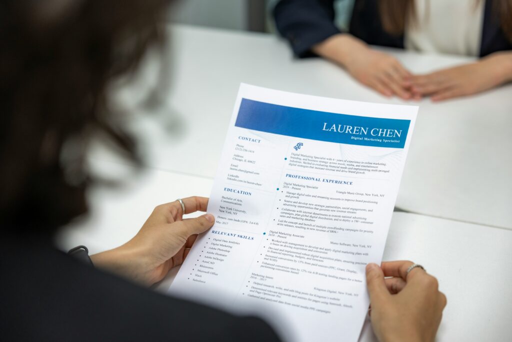 A woman reads a resume at a table during a job interview.