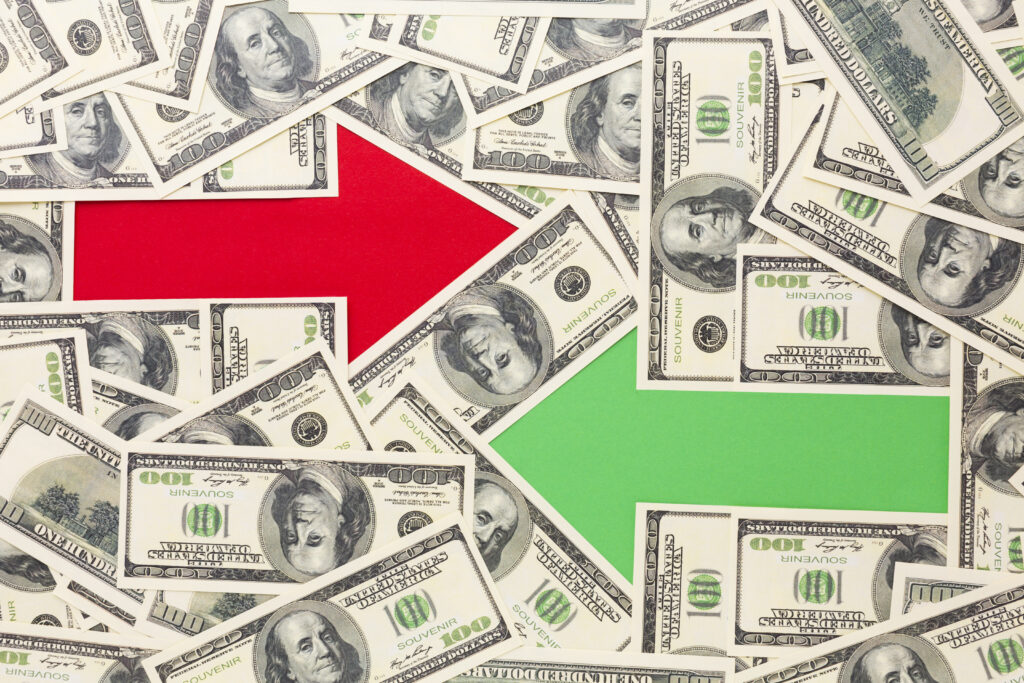 Banknotes overlaid by a red arrow pointing one way (indicating outflows) and a green arrow pointing another way (indicating inflows).