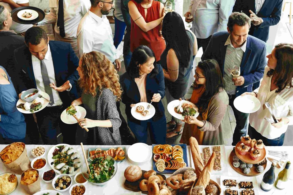 Guests in business attire gather around a large buffet table filled with diverse food options.